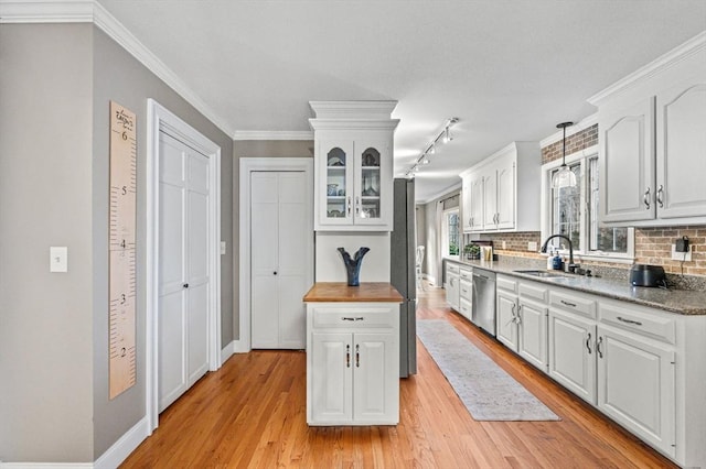 kitchen featuring sink, white cabinetry, stainless steel dishwasher, decorative backsplash, and pendant lighting