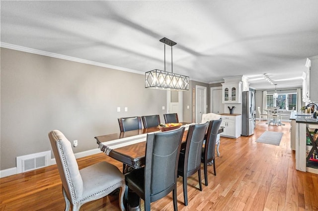 dining room with light hardwood / wood-style floors and crown molding