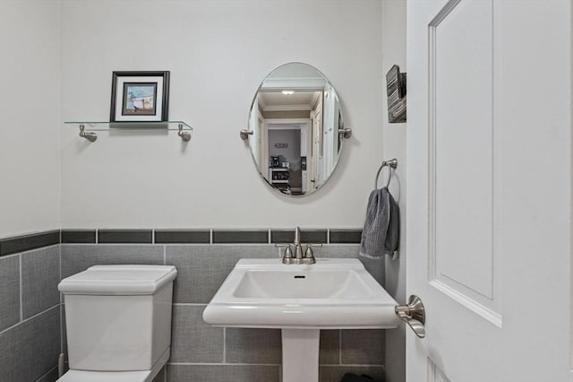 bathroom featuring toilet, sink, tile walls, and ornamental molding