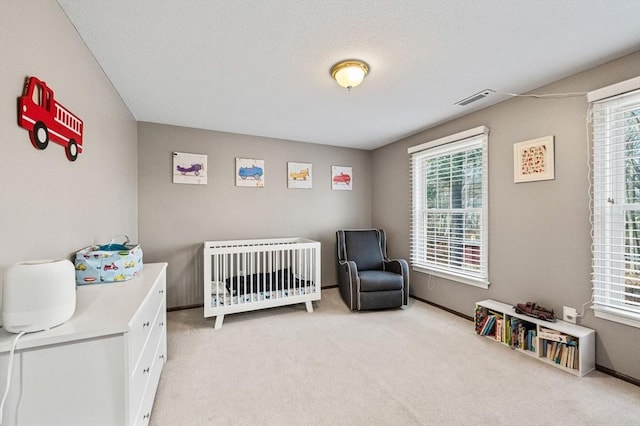 bedroom featuring a nursery area and light carpet