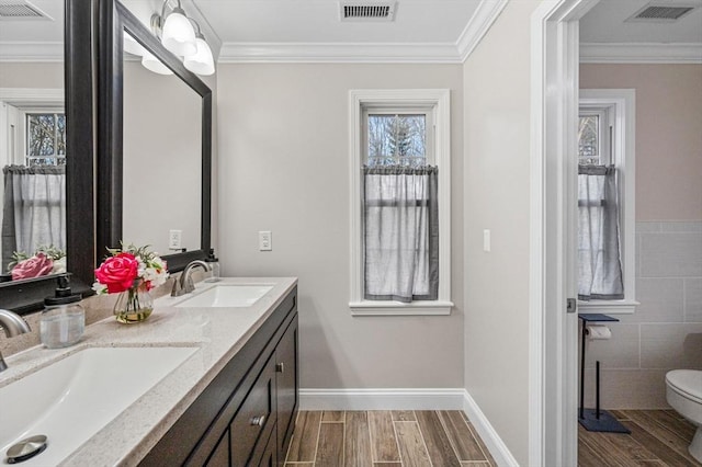 bathroom with toilet, vanity, and ornamental molding