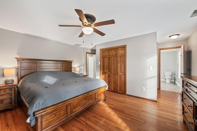 bedroom with ceiling fan, light wood-type flooring, a closet, and ensuite bath