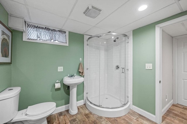 bathroom featuring toilet, an enclosed shower, and a drop ceiling