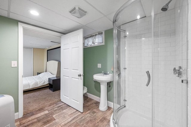 bathroom with a shower with door, a paneled ceiling, toilet, and wood-type flooring