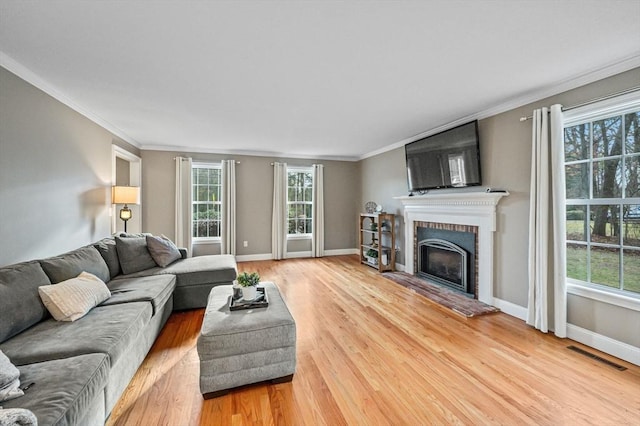 living room featuring a fireplace, crown molding, and hardwood / wood-style flooring