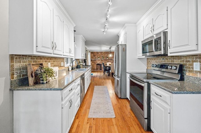 kitchen with sink, white cabinetry, dark stone countertops, light hardwood / wood-style flooring, and appliances with stainless steel finishes