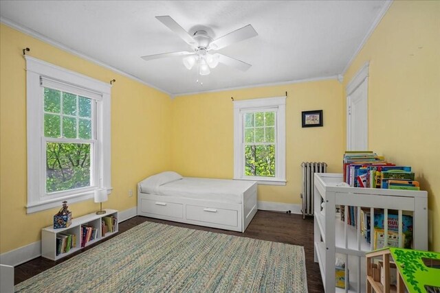 bedroom with ornamental molding, dark wood-style flooring, baseboards, ceiling fan, and radiator heating unit