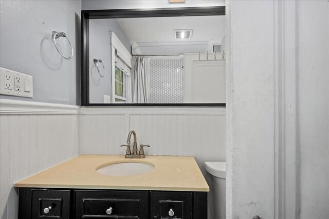 full bath with wainscoting, vanity, a shower with curtain, and toilet