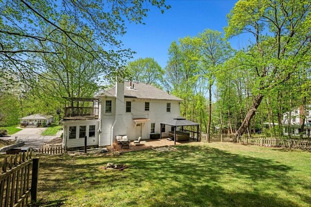 back of house with a fenced backyard, a patio, a gazebo, and a yard