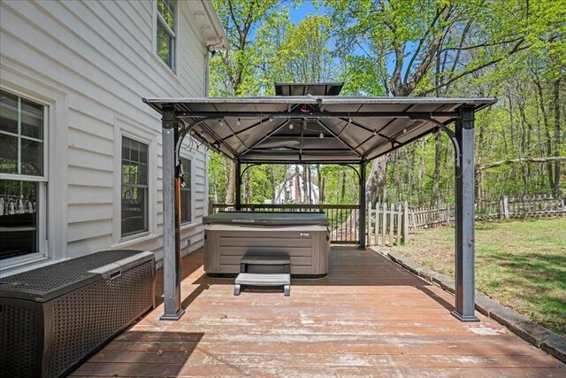 view of patio / terrace featuring a gazebo, a hot tub, a wooden deck, and fence
