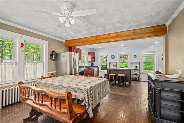 bedroom with radiator heating unit, multiple windows, freestanding refrigerator, and dark wood-type flooring