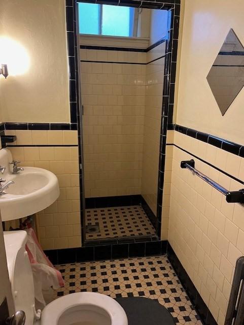 bathroom with tile walls, sink, toilet, and walk in shower