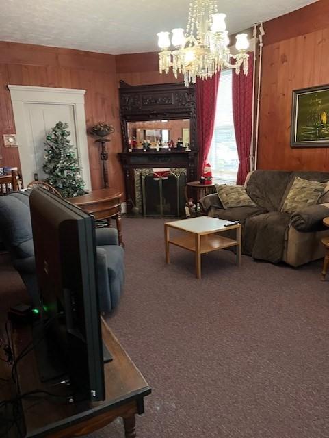 carpeted living room with a multi sided fireplace, a chandelier, and wood walls