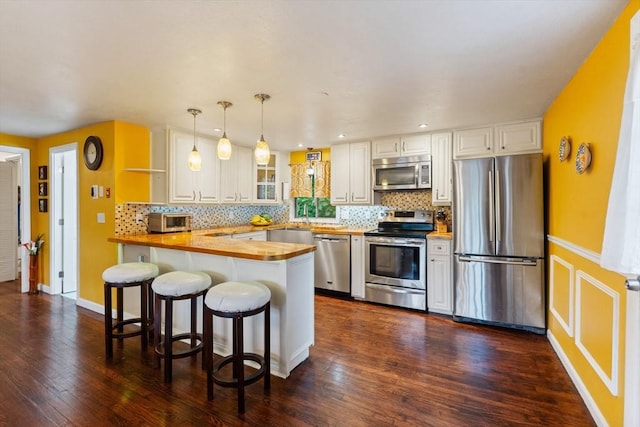 44 Drexel St, Worcester, MA 01602 - kitchen featuring appliances with stainless steel finishes, a peninsula, dark wood-style floors, backsplash, and recessed lighting