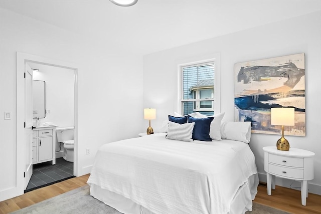 bedroom with ensuite bathroom and wood finished floors