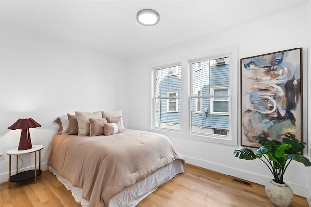 bedroom with baseboards, light wood-type flooring, and visible vents