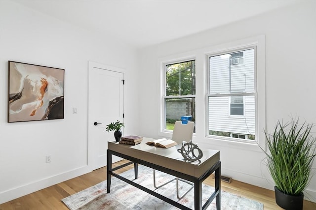 office with baseboards, light wood finished floors, and visible vents