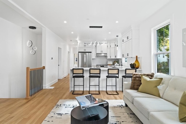 living room with recessed lighting, baseboards, and light wood-type flooring
