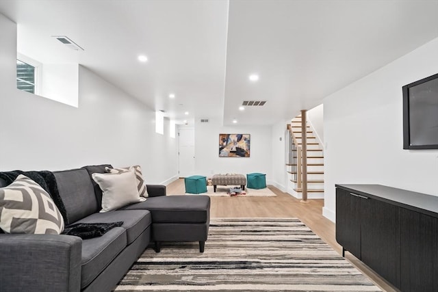 living area featuring recessed lighting, visible vents, light wood-style flooring, and stairway