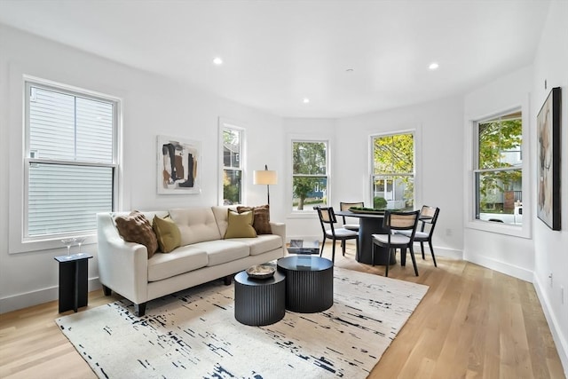 living room featuring baseboards, light wood-style flooring, and a wealth of natural light
