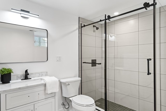 bathroom with a shower with door, vanity, and toilet