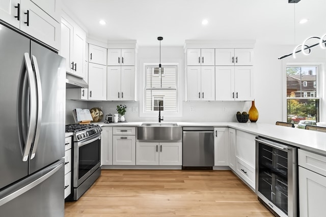 kitchen featuring white cabinetry, stainless steel appliances, pendant lighting, and beverage cooler