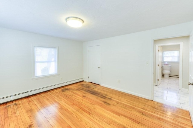 empty room with a baseboard heating unit and light hardwood / wood-style floors