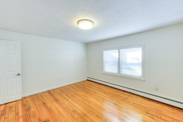 spare room featuring a baseboard radiator and light hardwood / wood-style floors