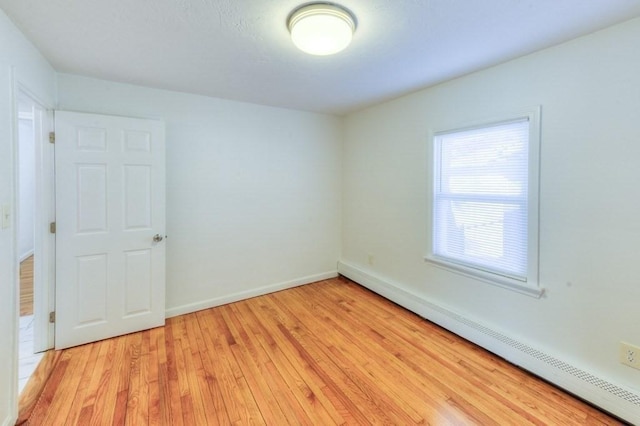 unfurnished room with a baseboard radiator and light hardwood / wood-style floors