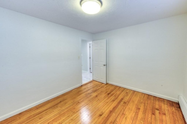 spare room with light wood-type flooring and baseboard heating