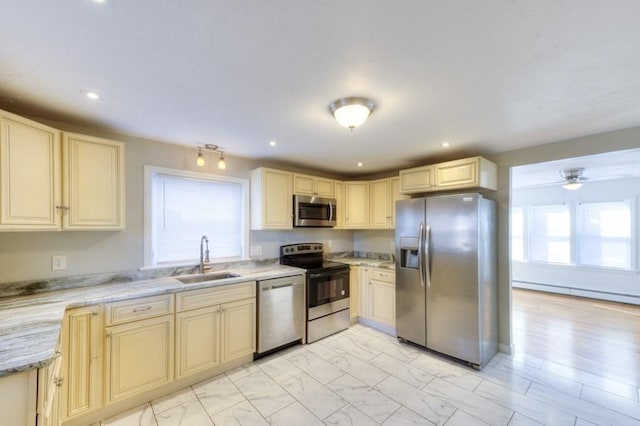 kitchen with sink, ceiling fan, appliances with stainless steel finishes, a baseboard heating unit, and light stone counters