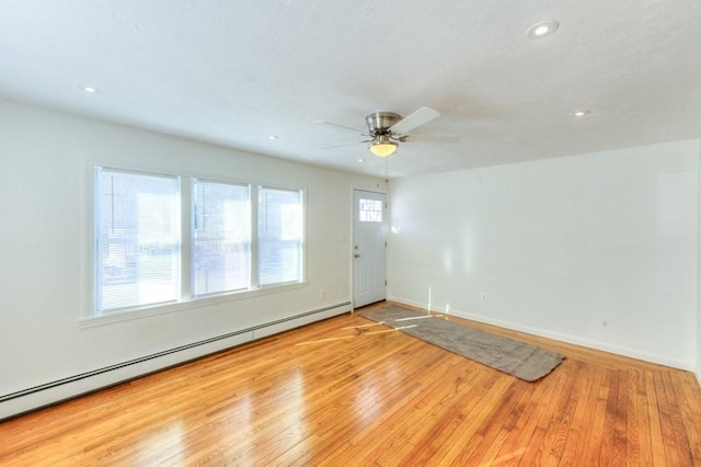 empty room featuring a baseboard heating unit, light hardwood / wood-style flooring, and ceiling fan