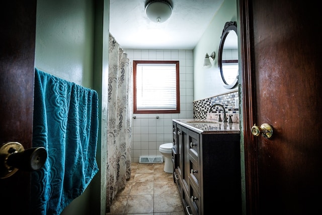 bathroom featuring tile patterned flooring, vanity, toilet, and tile walls