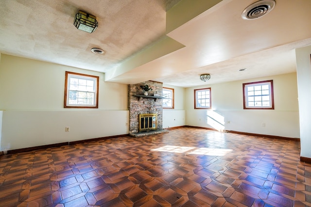 unfurnished living room featuring a wealth of natural light, a fireplace, and a textured ceiling