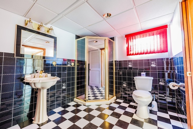 bathroom with an enclosed shower, a drop ceiling, toilet, and tile walls