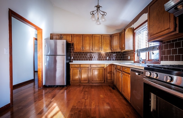 kitchen featuring ventilation hood, hanging light fixtures, dark hardwood / wood-style floors, tasteful backsplash, and stainless steel appliances