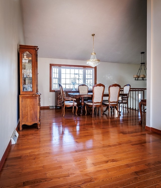 dining room with a chandelier, dark wood-type flooring, and lofted ceiling