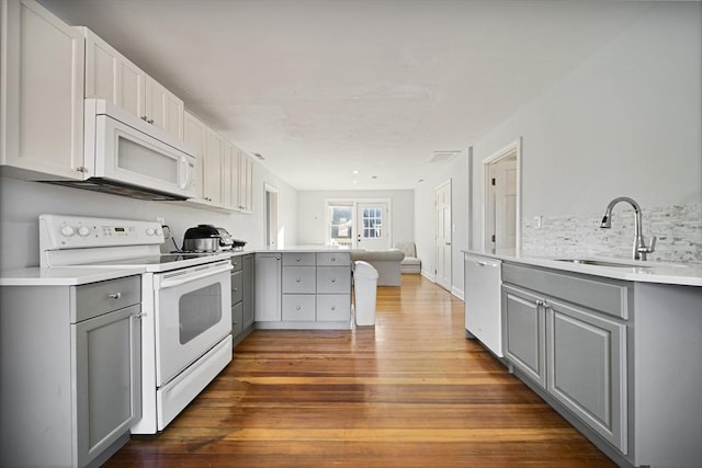 kitchen featuring white appliances, dark hardwood / wood-style floors, gray cabinetry, and sink