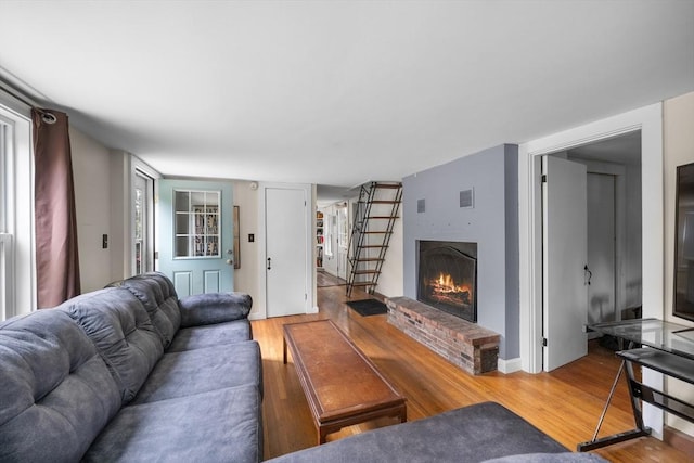 living room with a brick fireplace and hardwood / wood-style floors