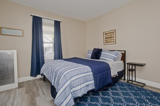 bedroom with baseboards, wood finished floors, and radiator