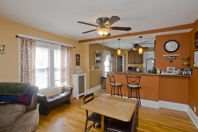 living room with light wood-type flooring, a ceiling fan, and baseboards