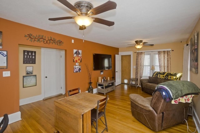 living room featuring light wood-style floors, baseboards, and ceiling fan