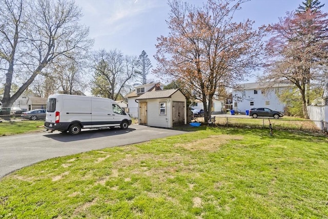 view of yard featuring fence, an outdoor structure, and a storage unit