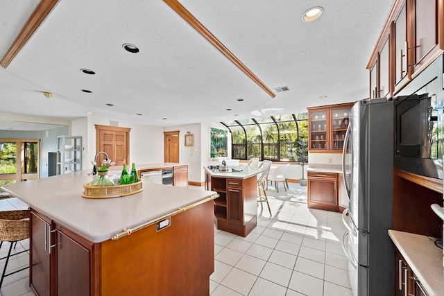 kitchen with a center island with sink, a breakfast bar area, stainless steel fridge, and plenty of natural light