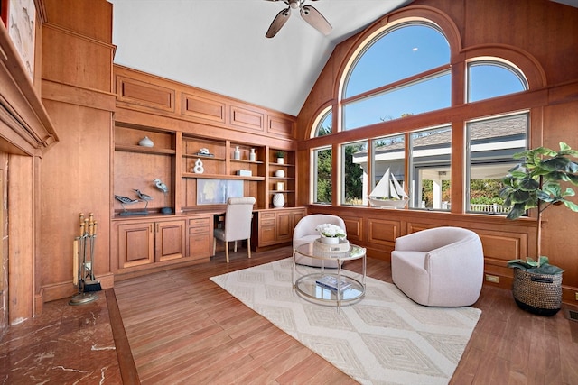 sitting room featuring ceiling fan, light wood-type flooring, built in desk, and built in features