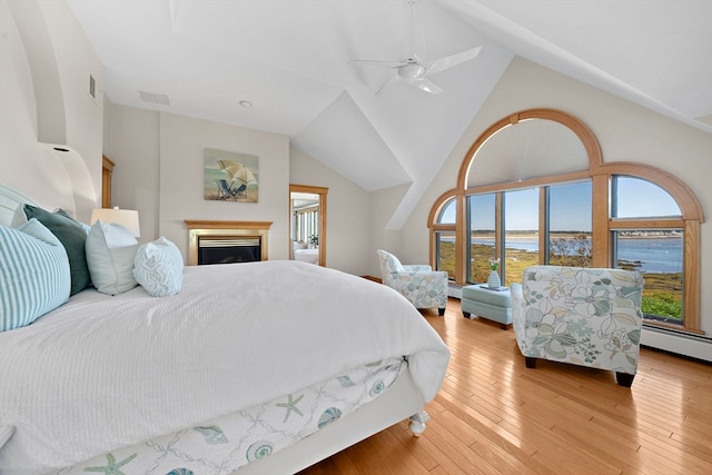 bedroom with ceiling fan, light hardwood / wood-style floors, a water view, and high vaulted ceiling