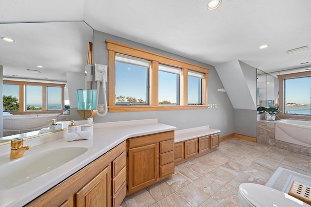 bathroom featuring vanity, plenty of natural light, toilet, and a bath