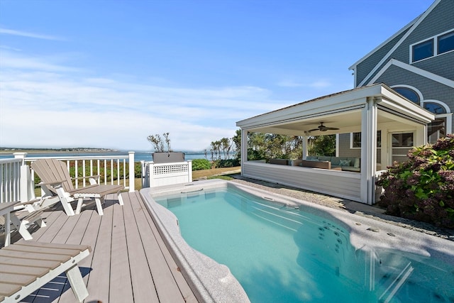 view of swimming pool featuring ceiling fan and a deck with water view