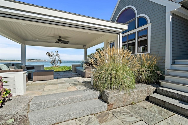 view of patio with a water view and ceiling fan