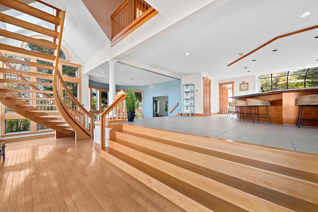 interior space featuring wood-type flooring, a high ceiling, and a healthy amount of sunlight